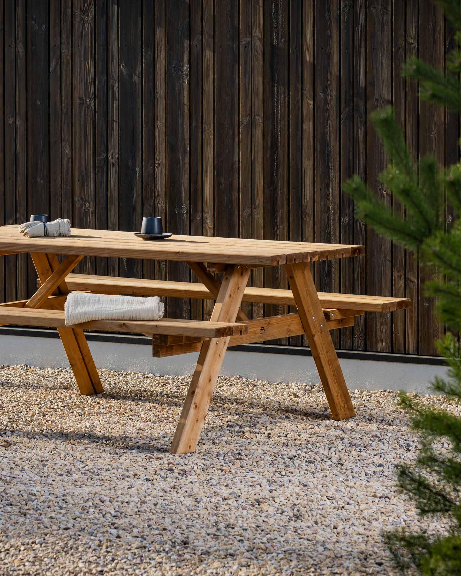 Brown picnic table against a wooden house wall