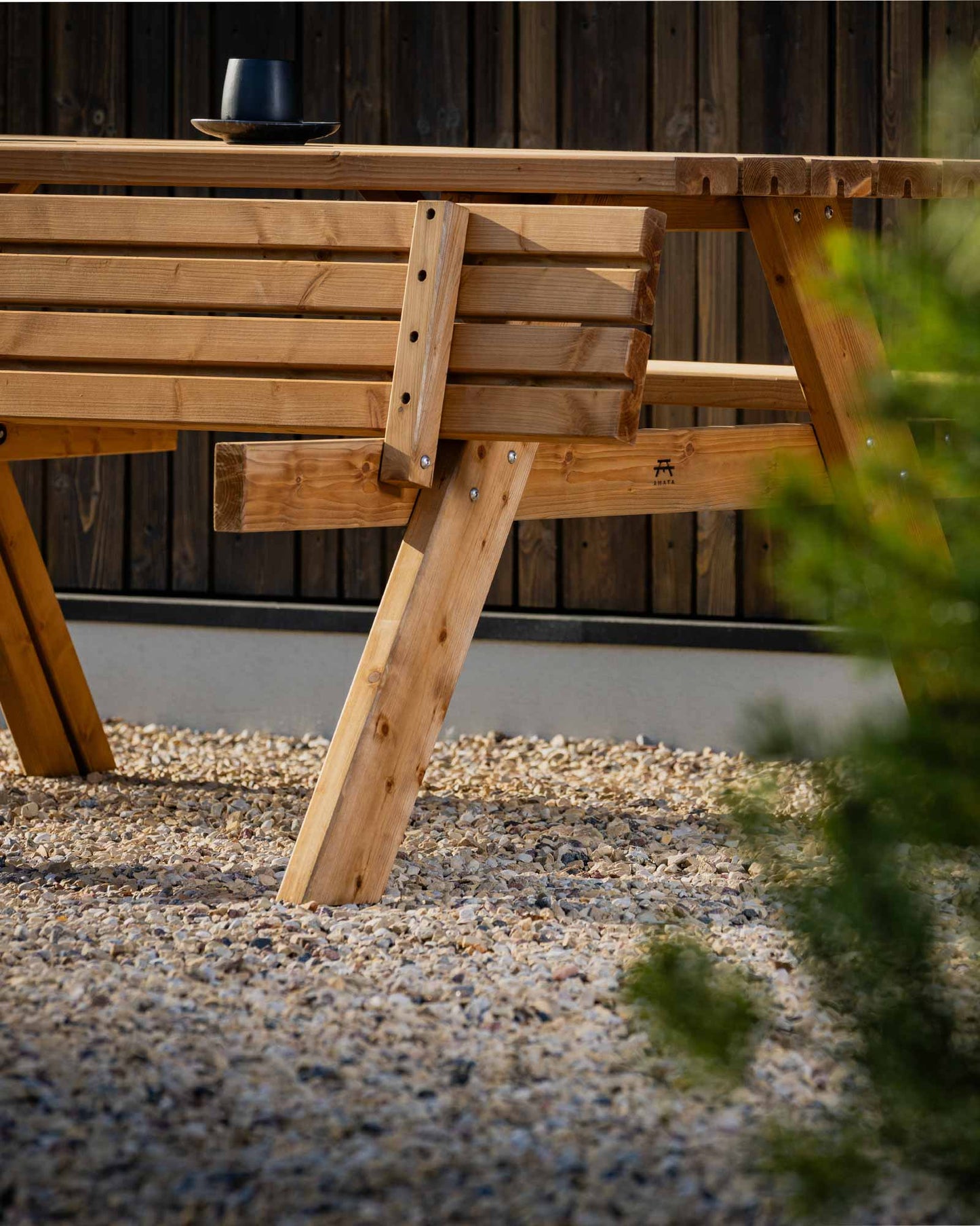 A-frame wooden picnic table photographed at a slight angle in a minimal garden setting