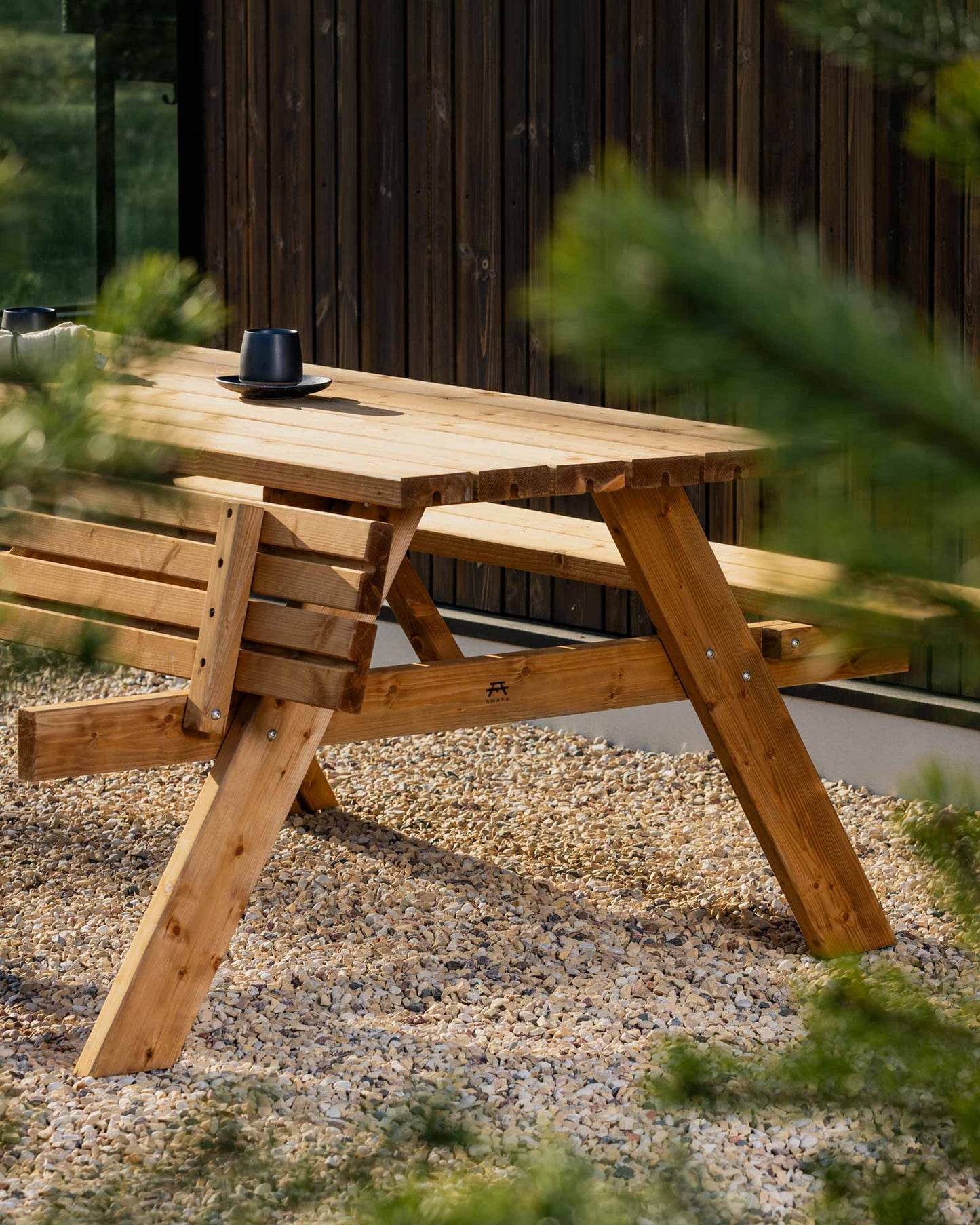 Brown garden picnic table standing on small pebbles in a garden