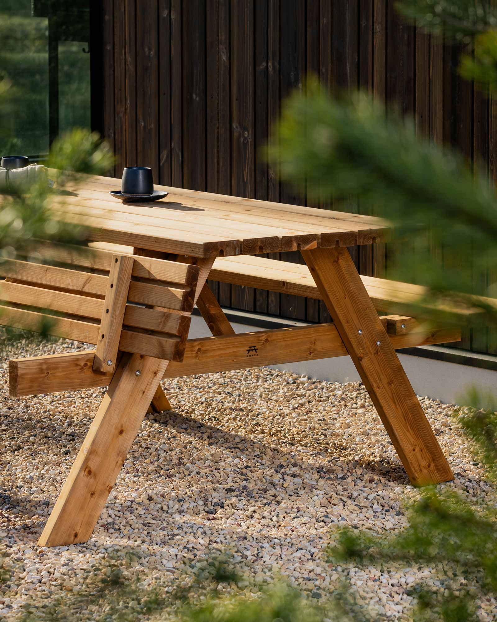 Brown garden picnic table standing on small pebbles in a garden