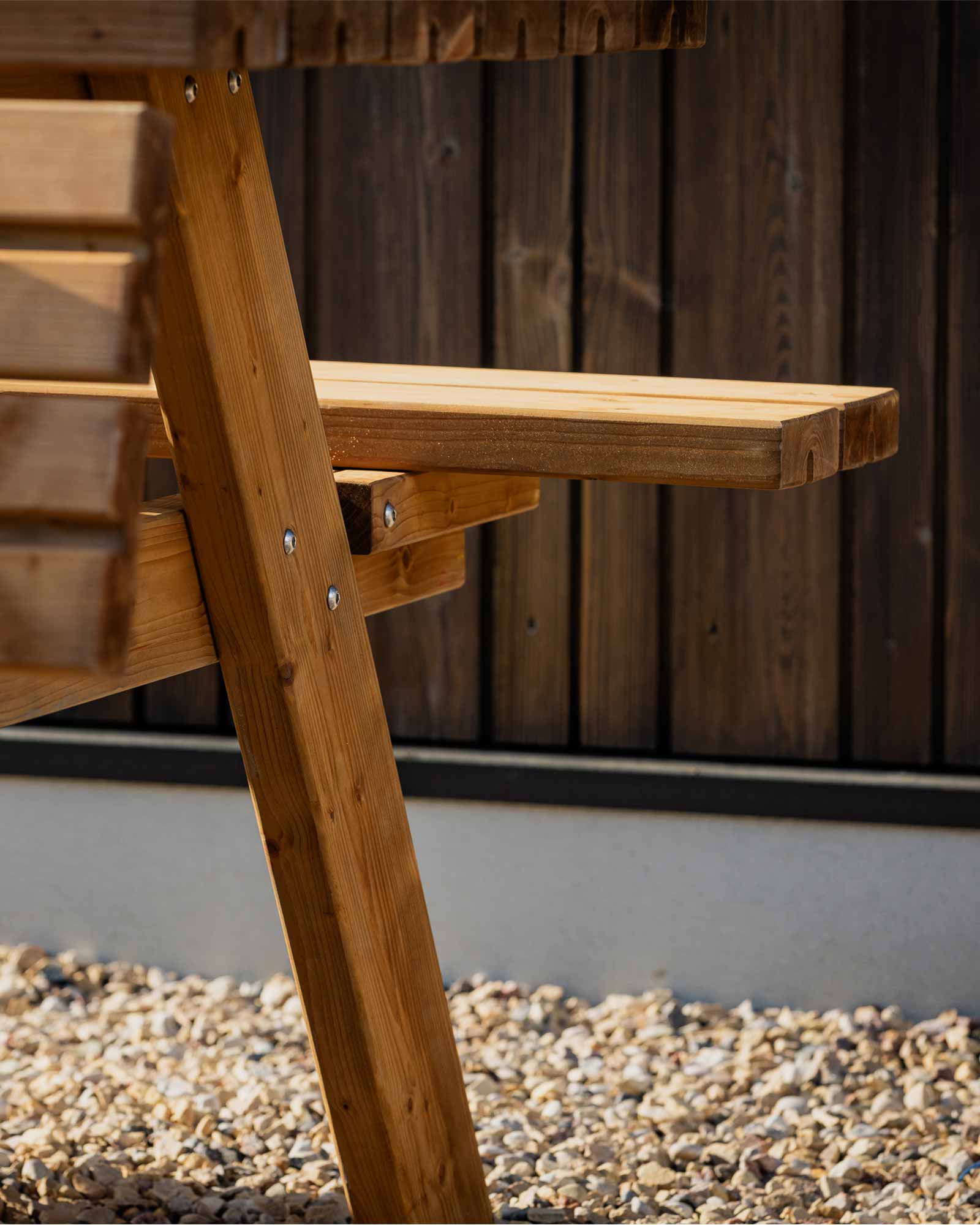 Closeup of the brown wooden picnic table's seating and fastenings