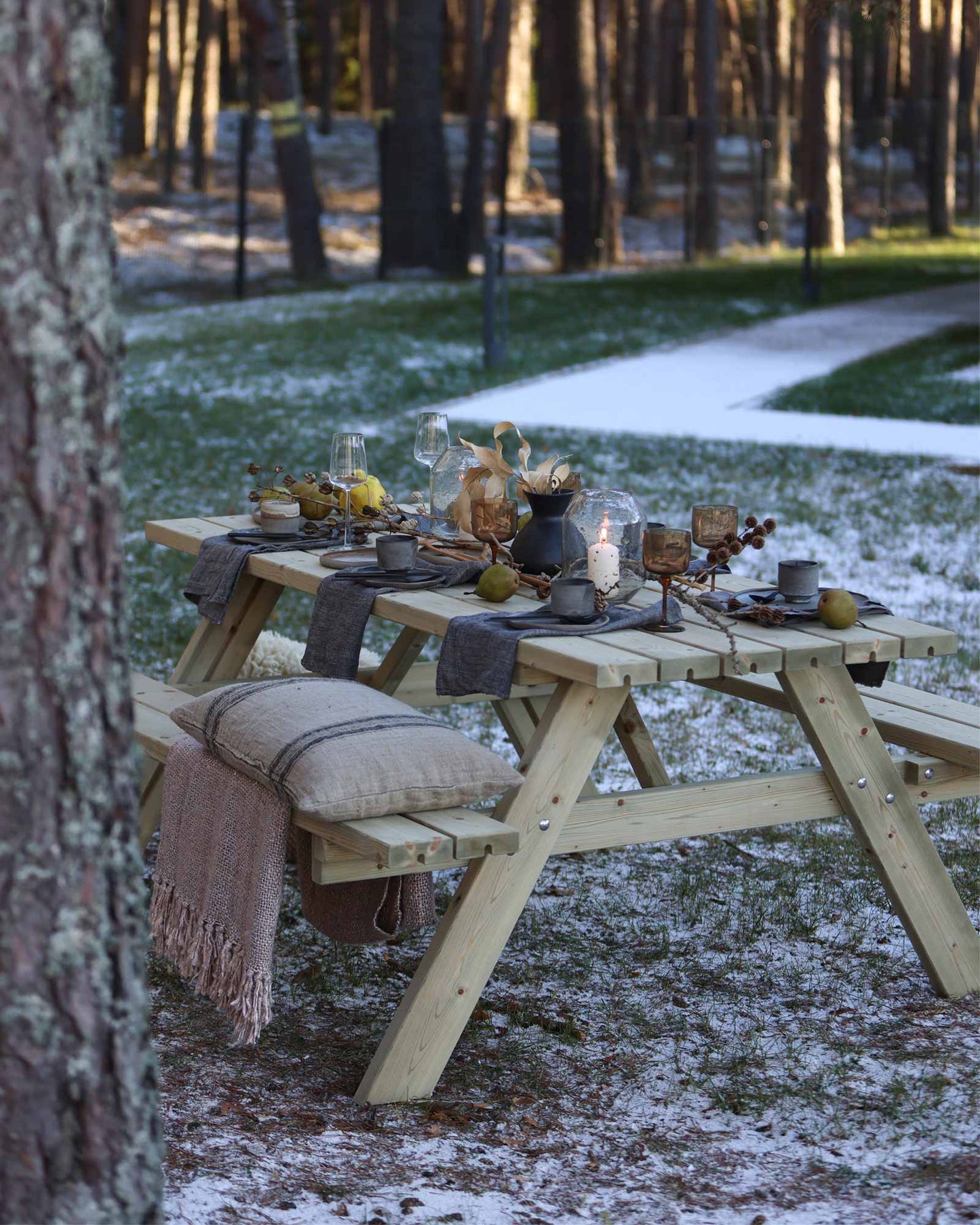 Green wooden picnic table set for dining with candles