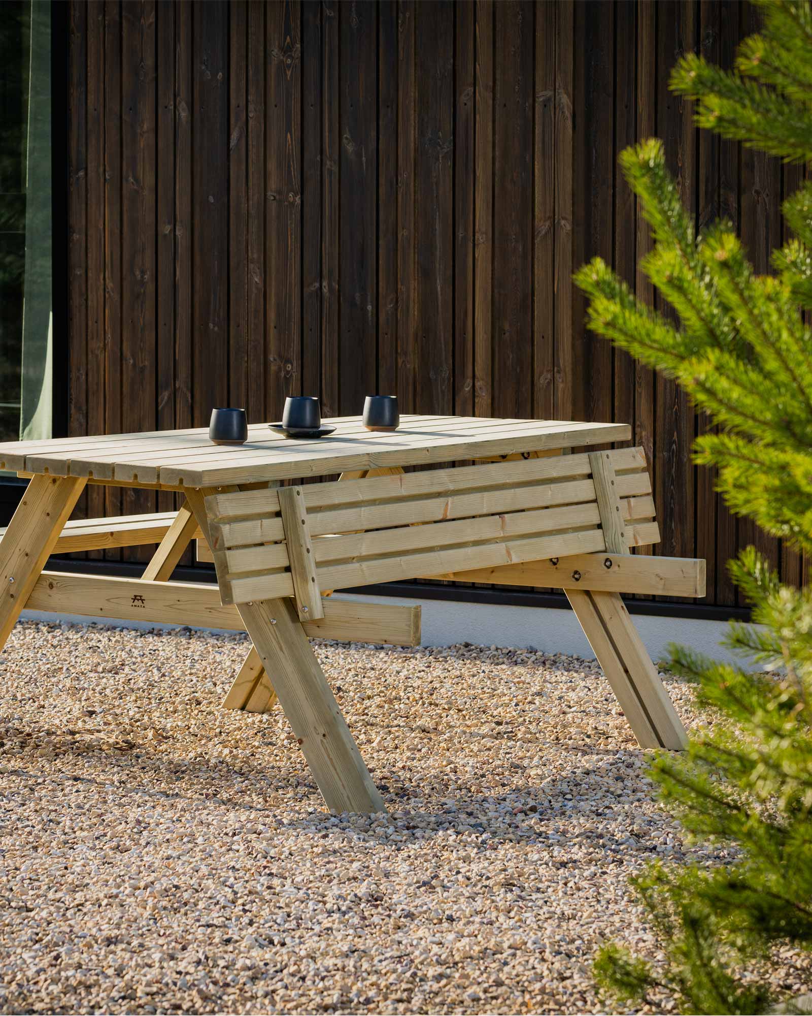 Green picnic table with 3 black bugs in a garden setting