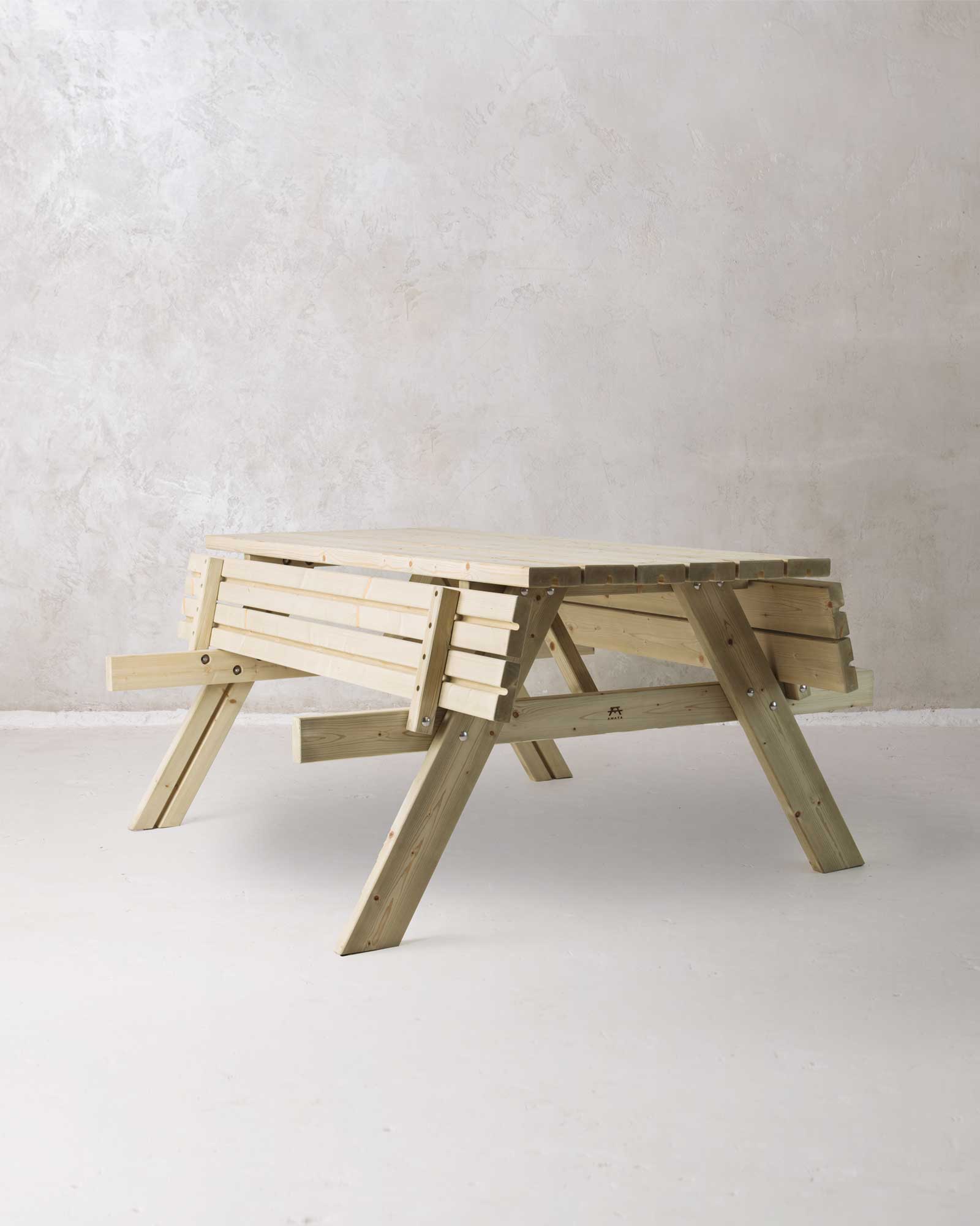 Green picnic table with folded benches on a concrete background, slightly turned at an angle