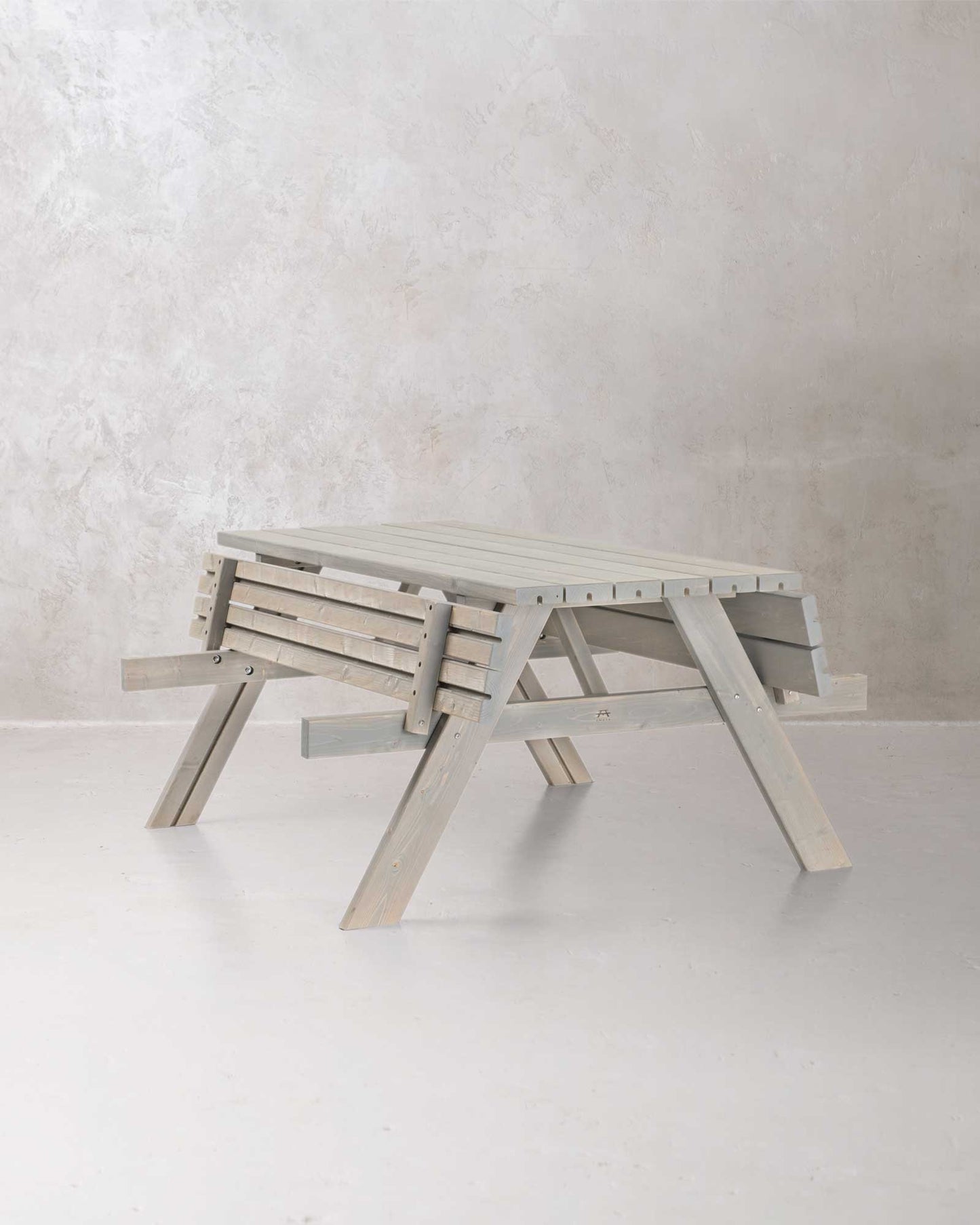 Grey picnic table with folded benches on a grey concrete background