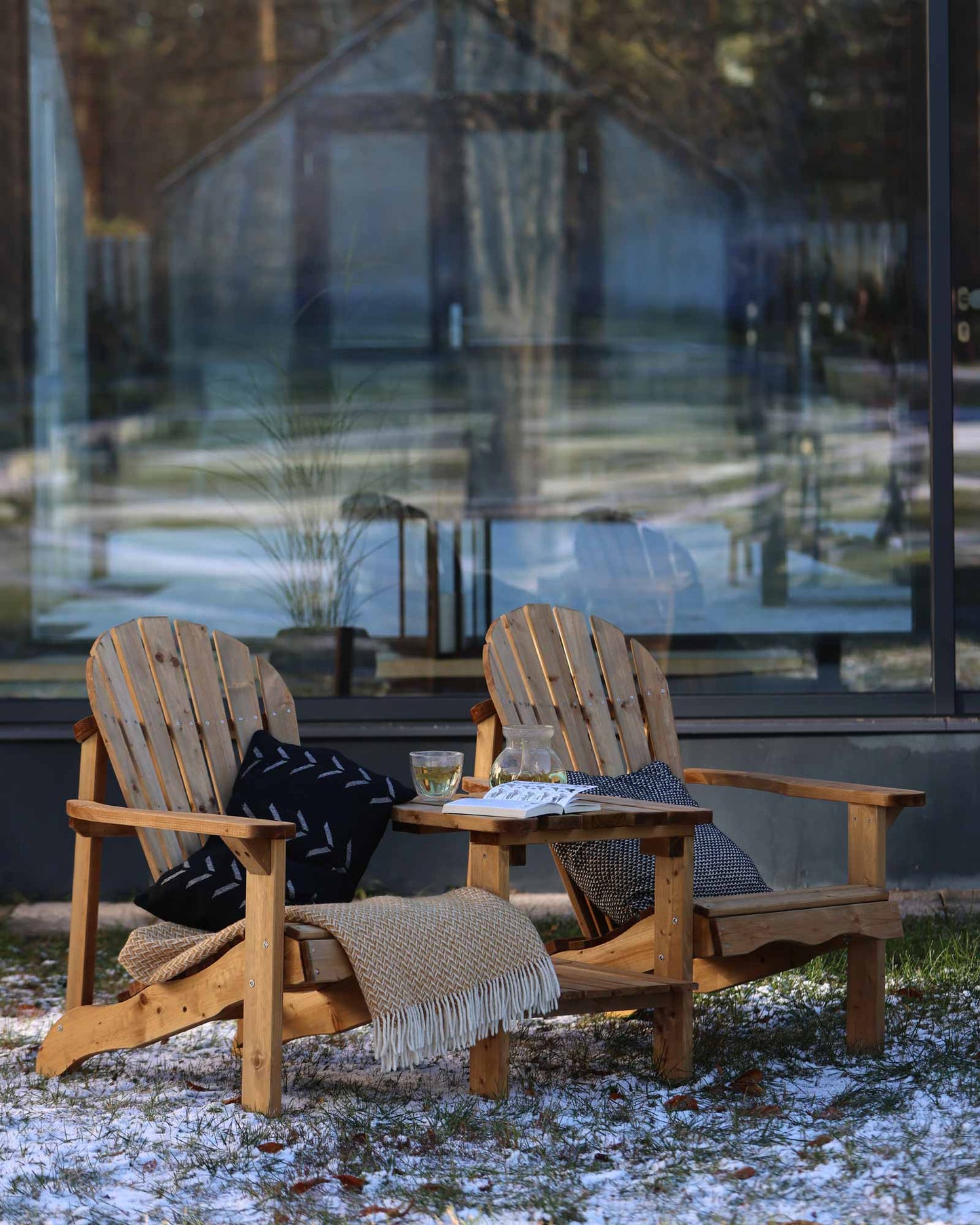 Brown double wooden Adirondack chair set with throw pillows and blankets, outside in winter