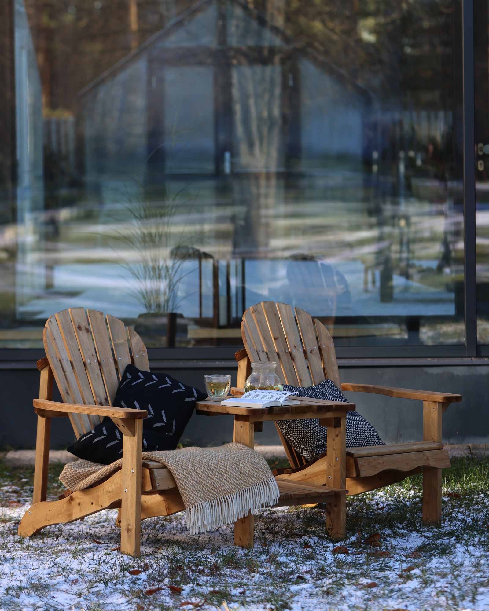 Brown double wooden Adirondack chair set with throw pillows and blankets, outside in winter