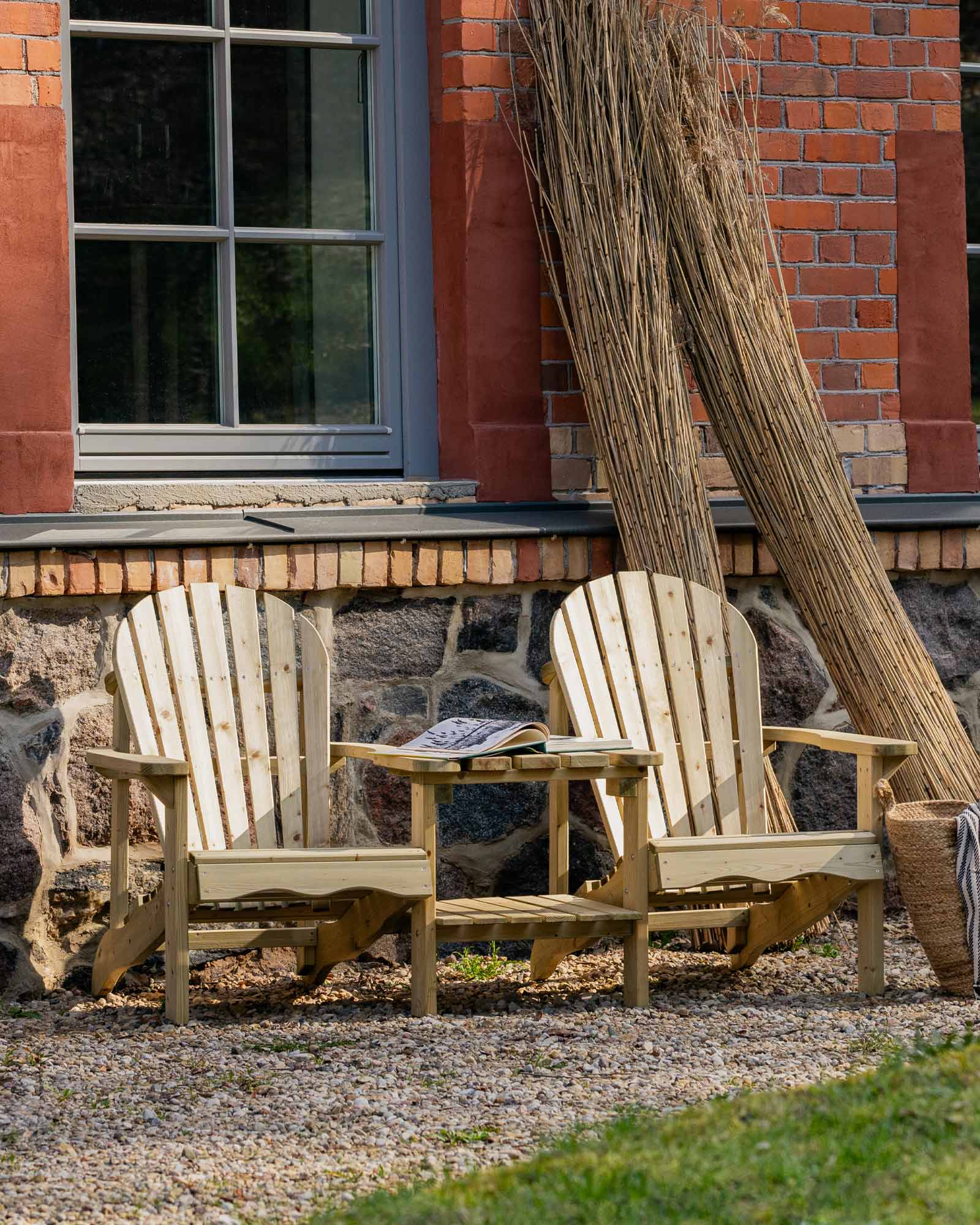 Double Adirondack chair set against an old timey red brick home