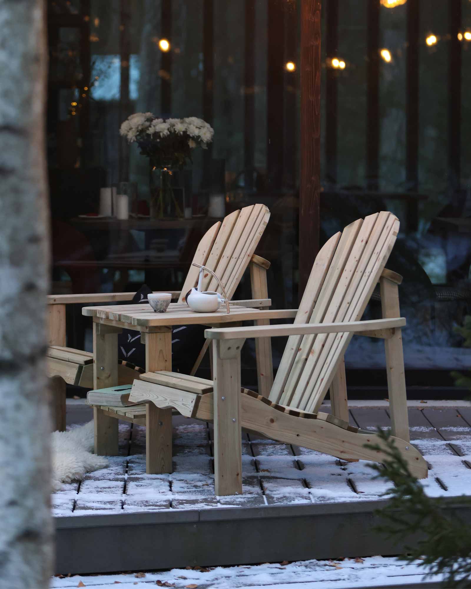 Green double wooden Adirondack chair set with a teapot and cup outside in winter