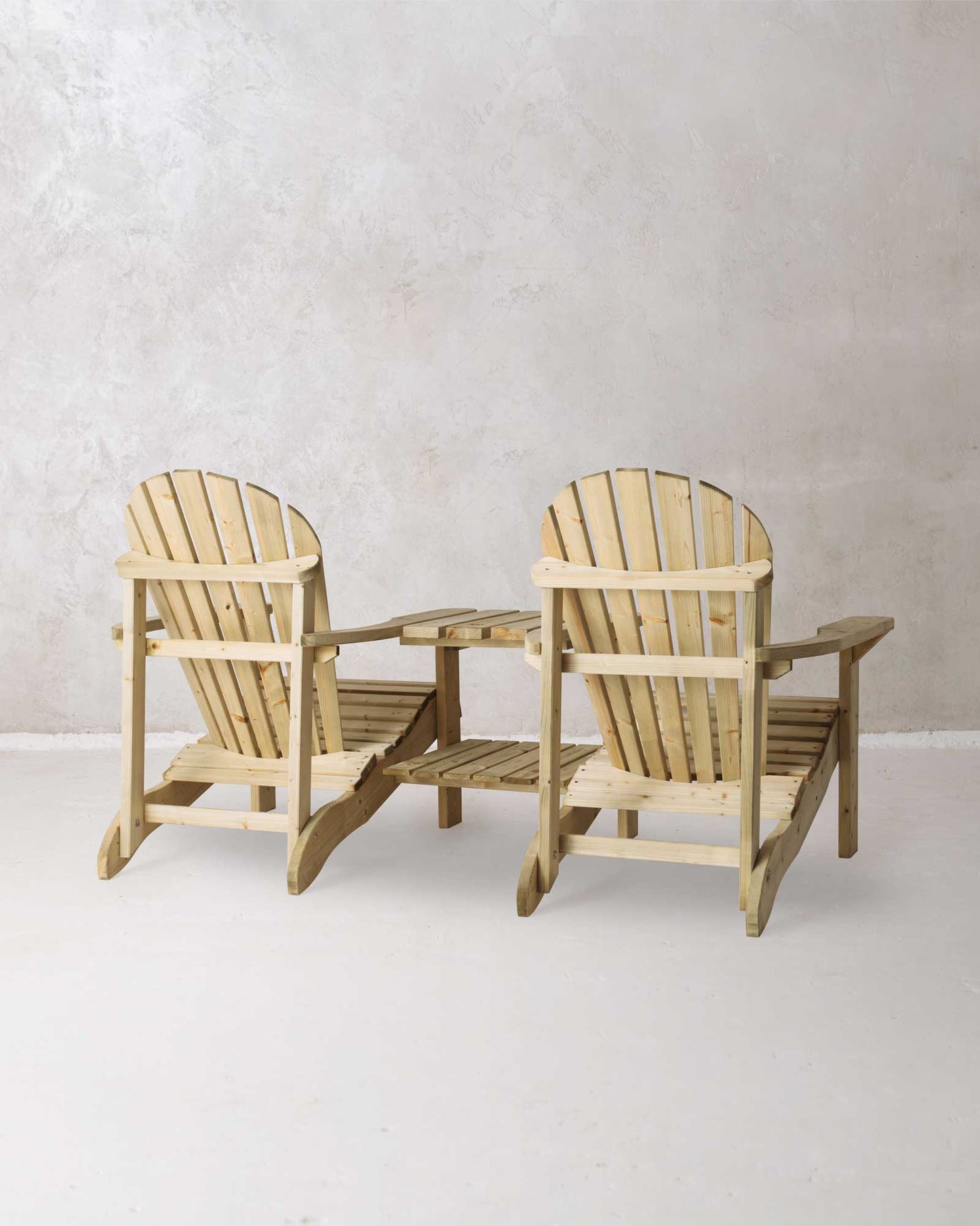 Double green Adirondack chair on a concrete background photographed from the back