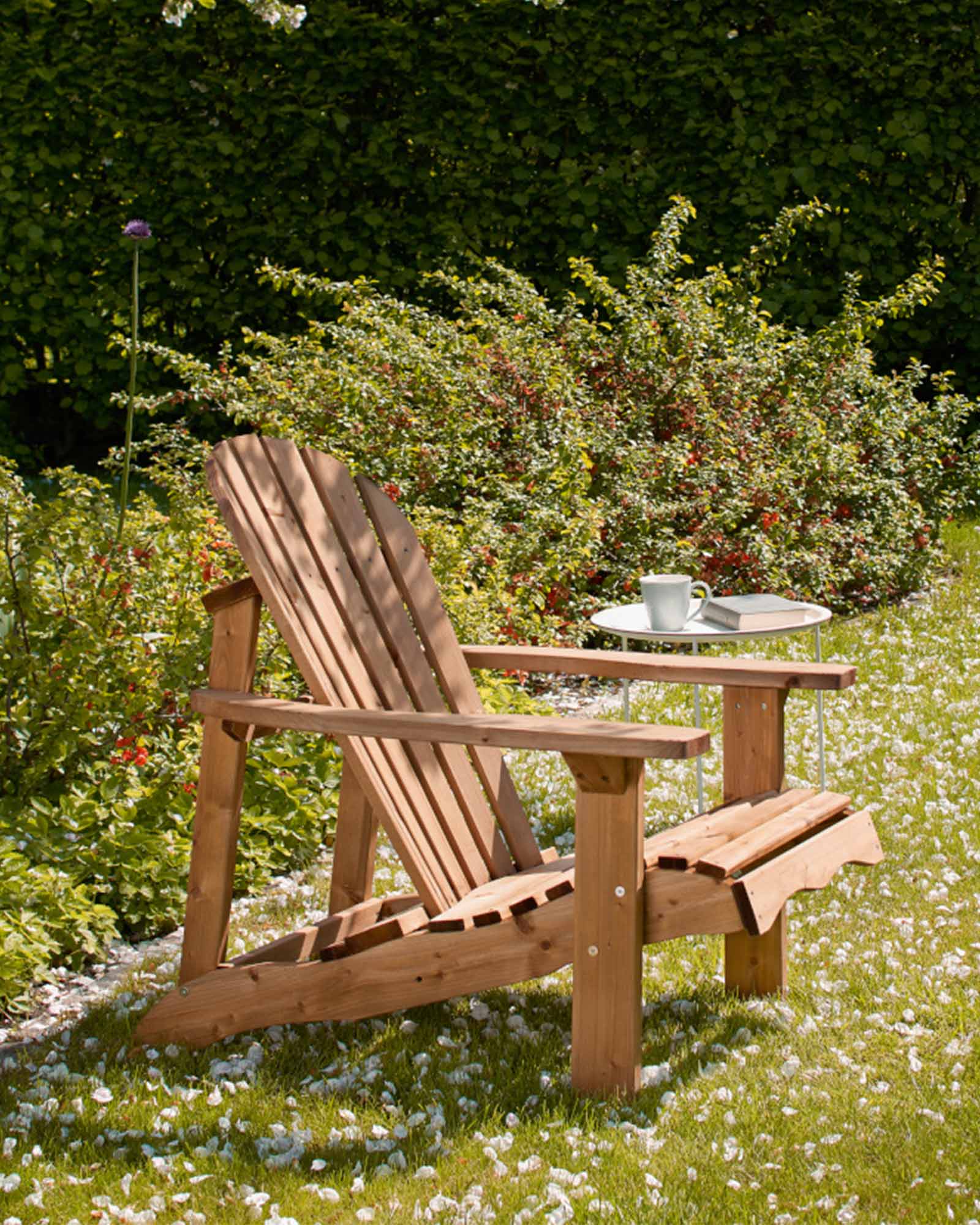 Brown Adirondack garden chair in a blooming garden