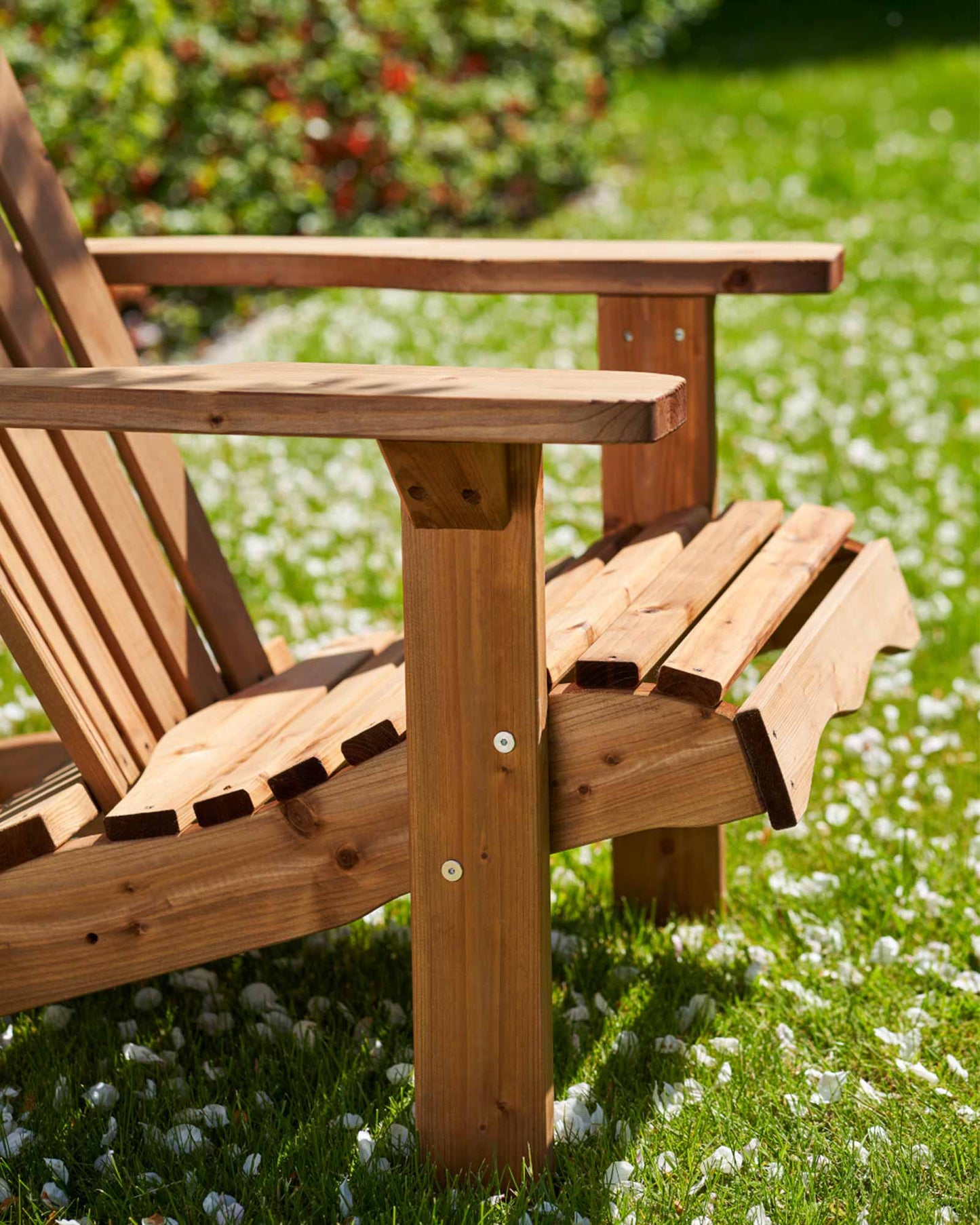 Brown Adirondack garden chair in green grass, closeup of the screw fastenings