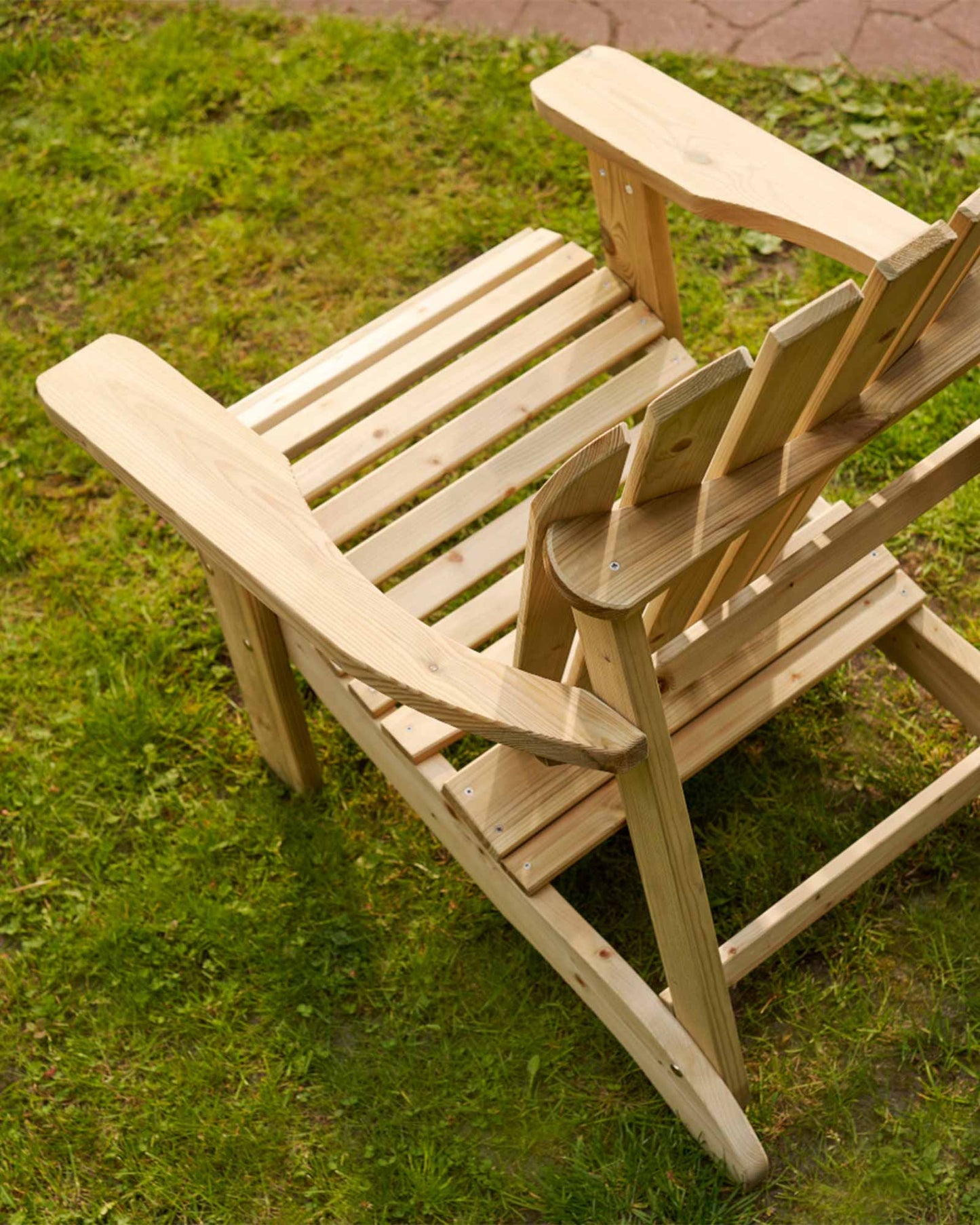 Green Adirondack chair photographed from above at a slight angle, sitting on the grass