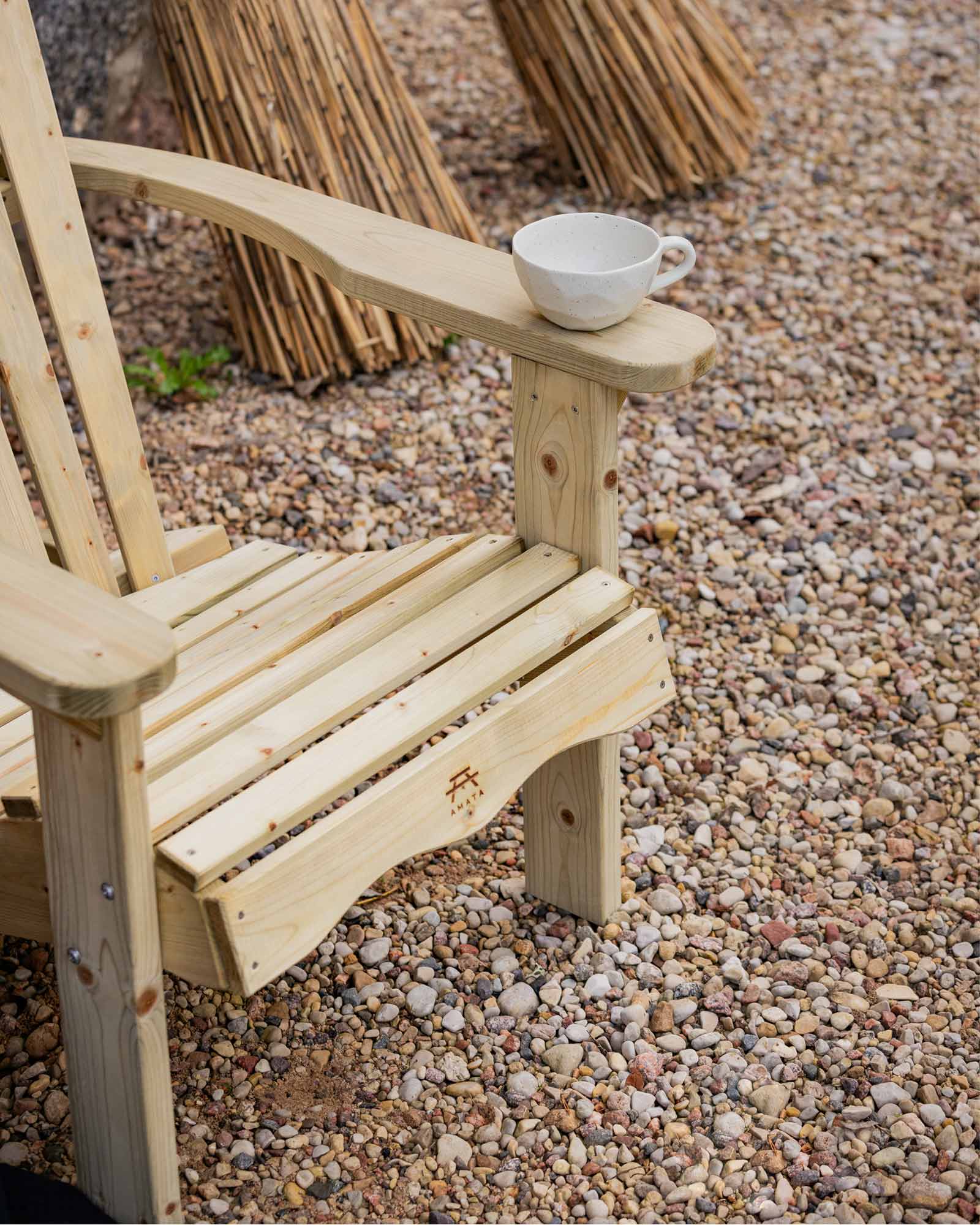 Green wooden Adirondack chair on a pebble floor