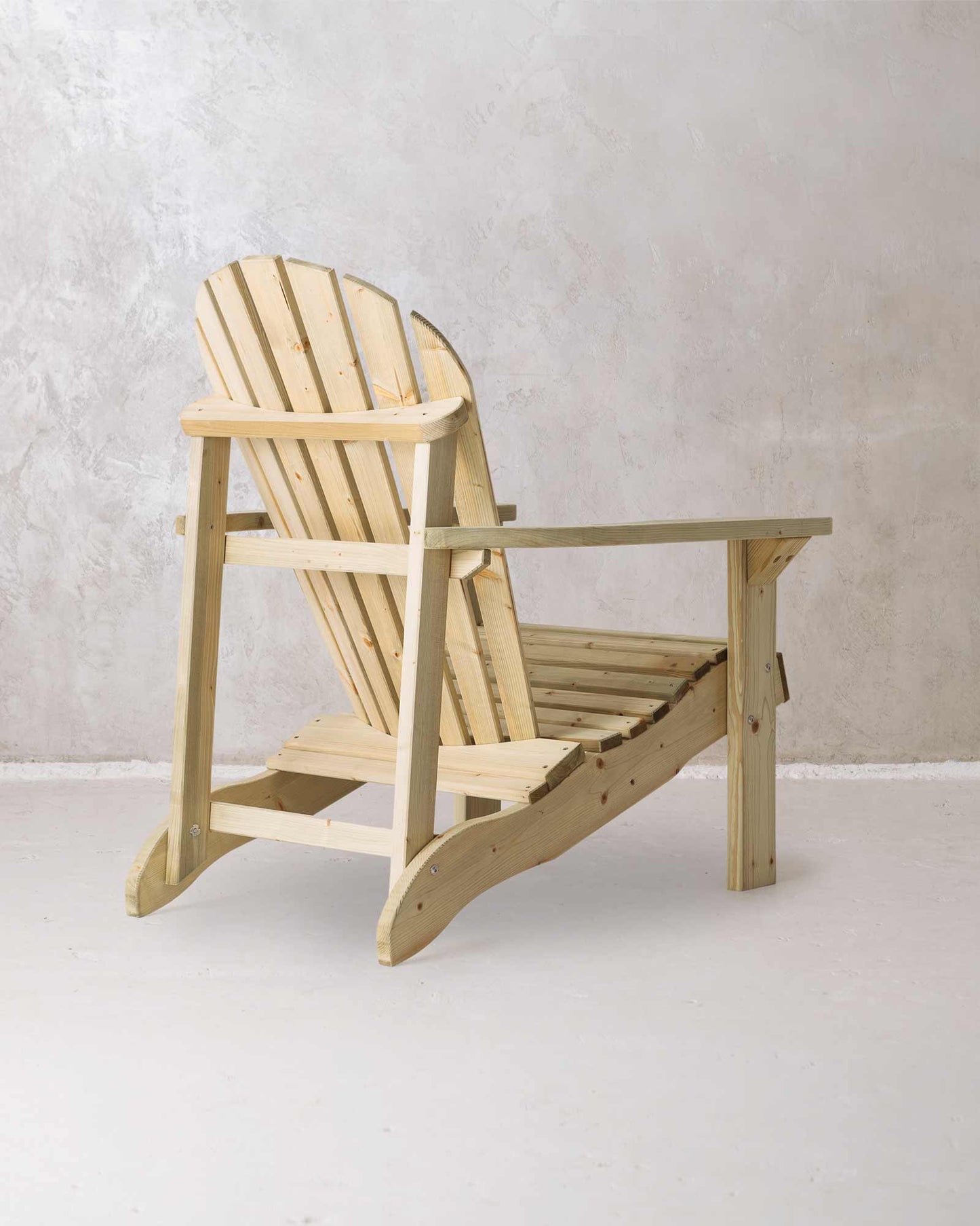 Green wooden Adirondack chair on a concrete background, photographed from the back and at a slight angle