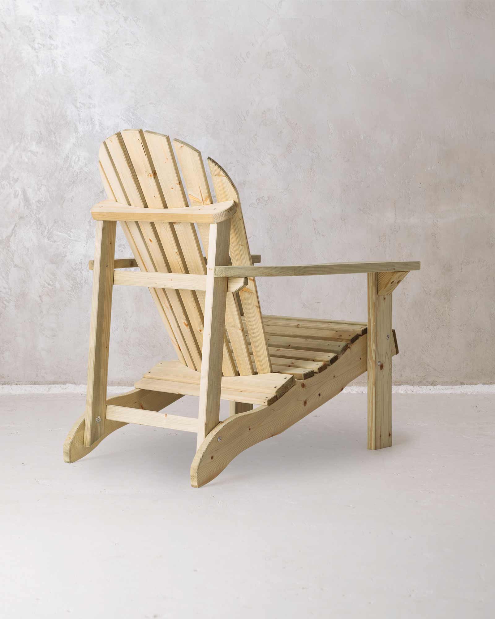 Green wooden Adirondack chair on a concrete background, photographed from the back and at a slight angle