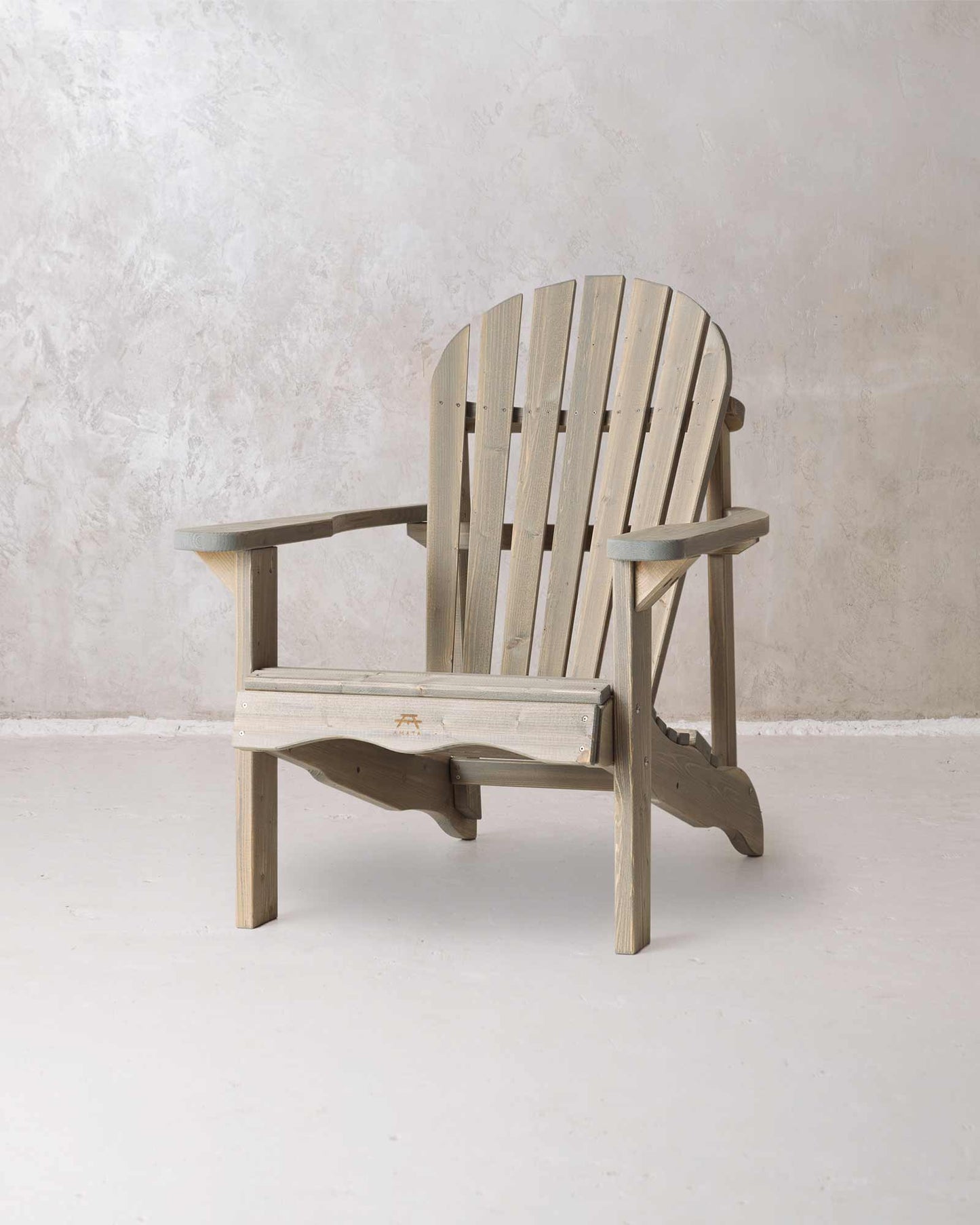 Grey wooden Adirondack chair on a concrete background, photographed from a slight angle