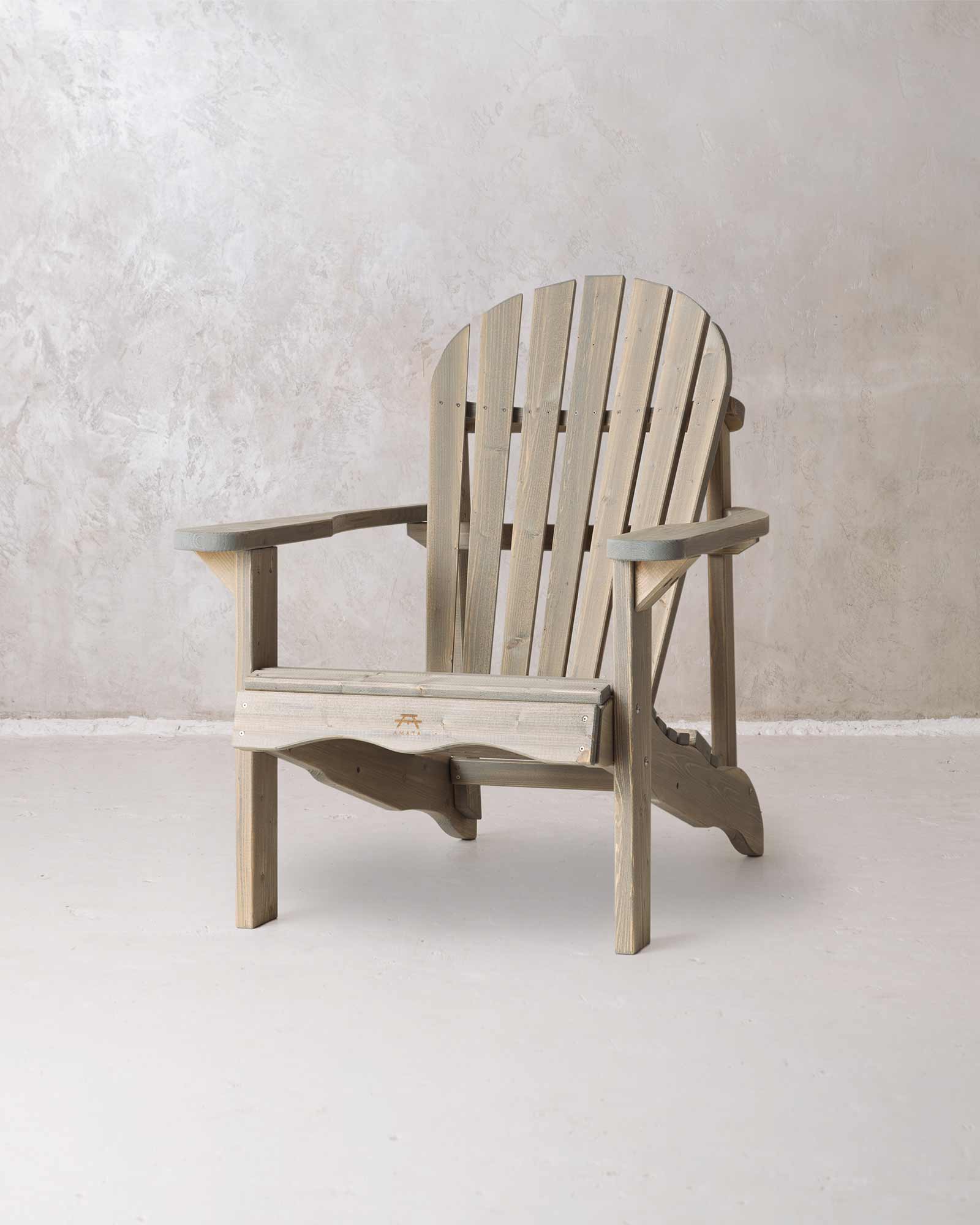 Grey wooden Adirondack chair on a concrete background, photographed from a slight angle