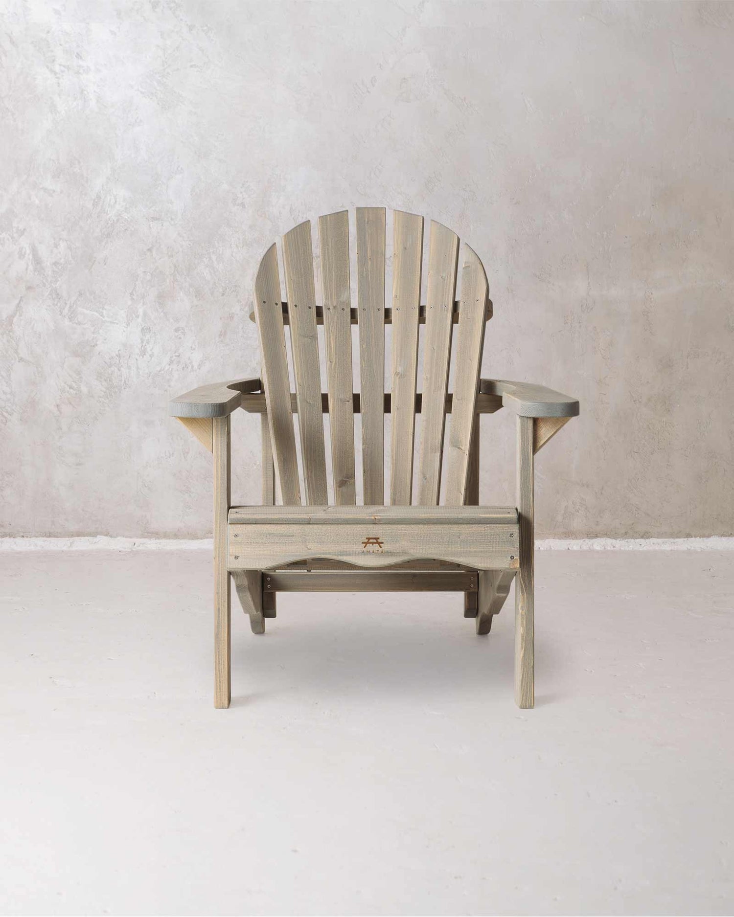 Grey wooden Adirondack chair on a concrete background, photographed from from the front