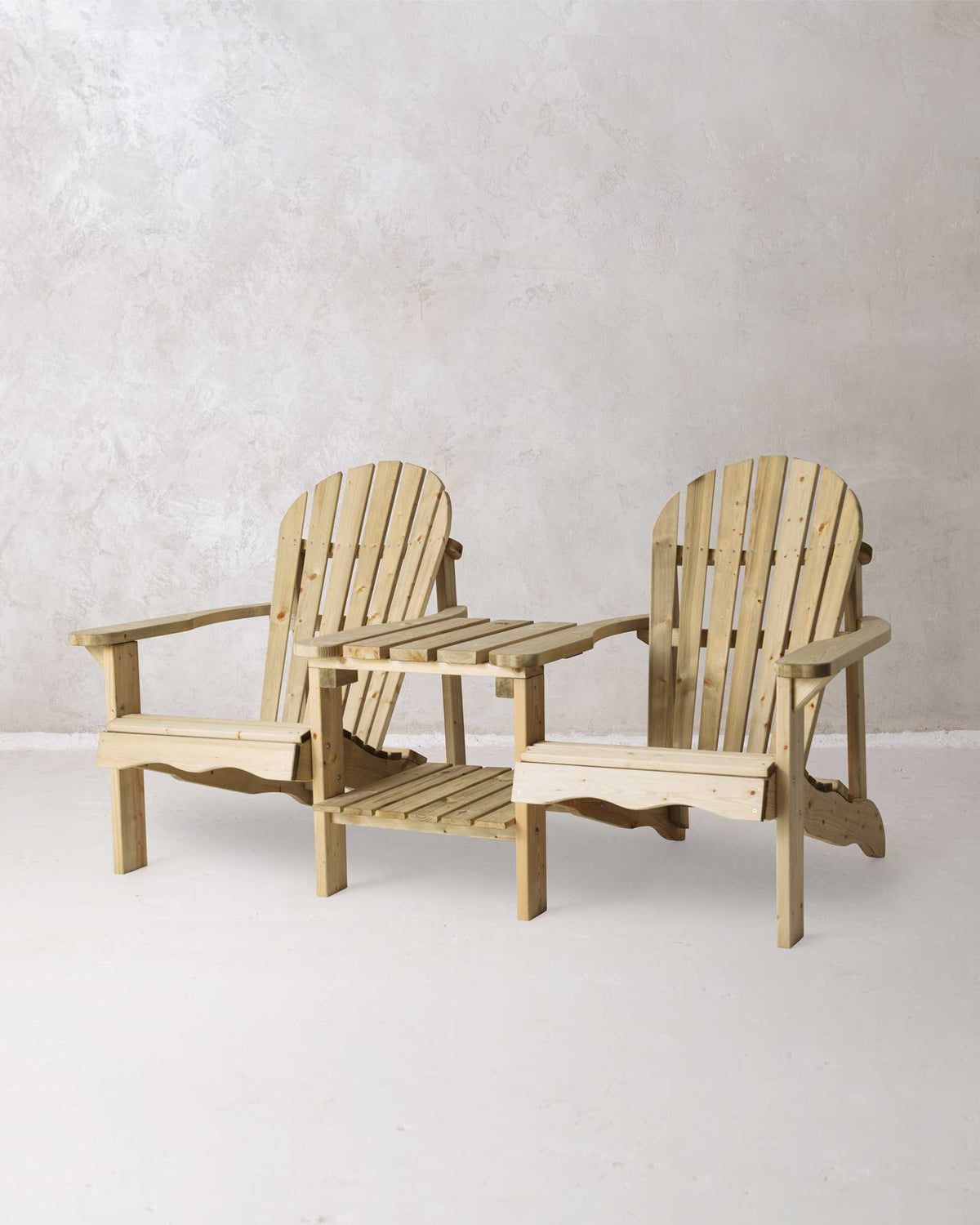 Double green Adirondack chair on a concrete background photographed at a slight angle