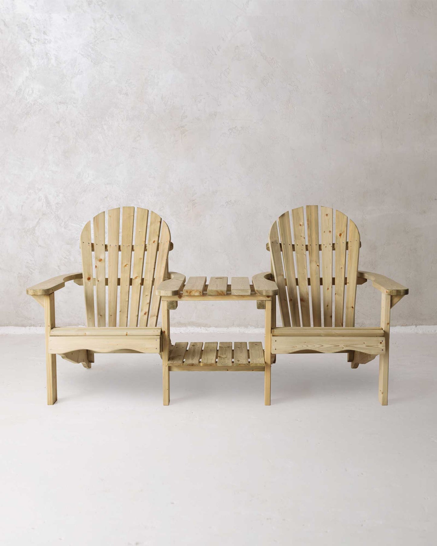 Double green Adirondack chair on a concrete background photographed from the front