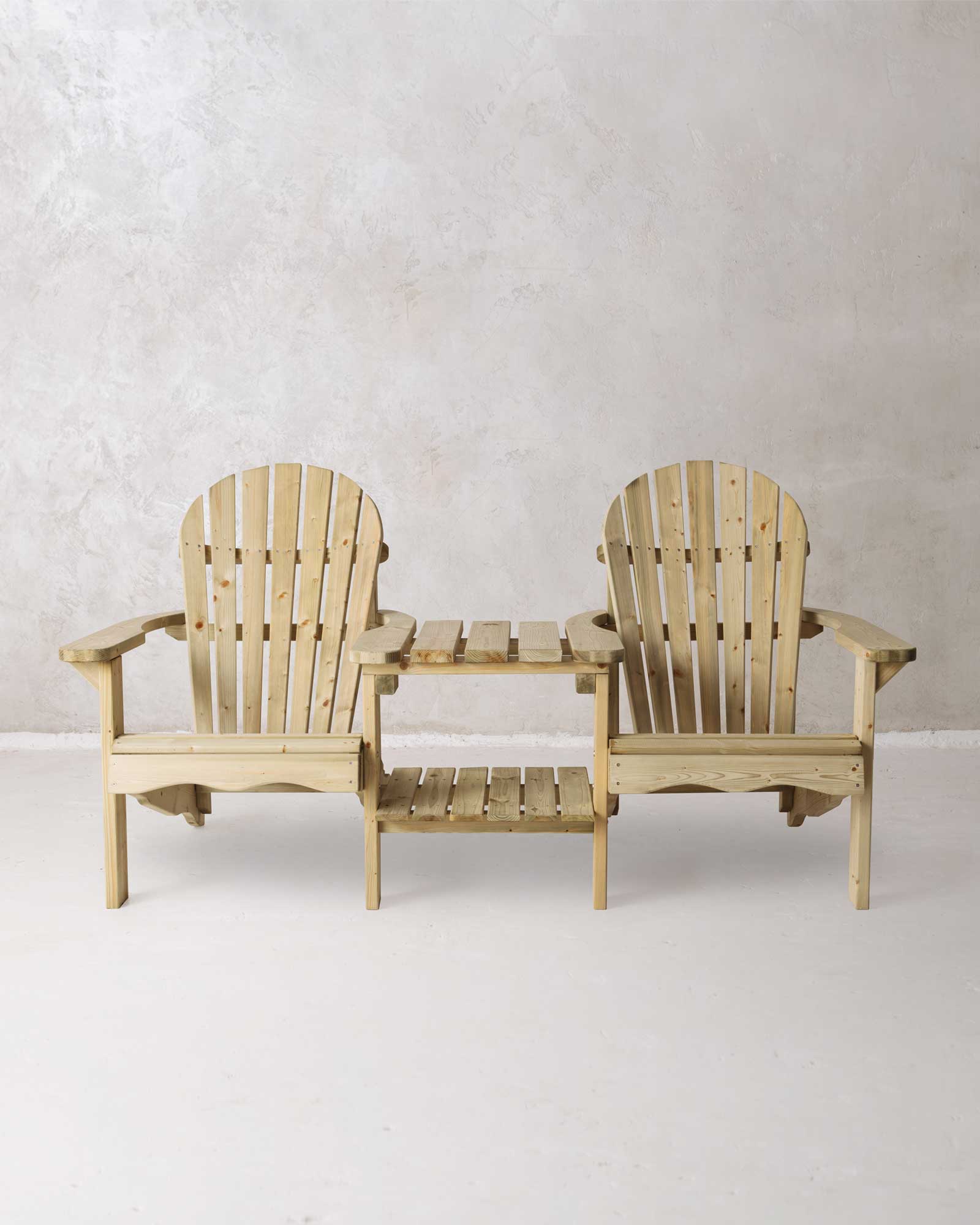Double green Adirondack chair on a concrete background photographed from the front