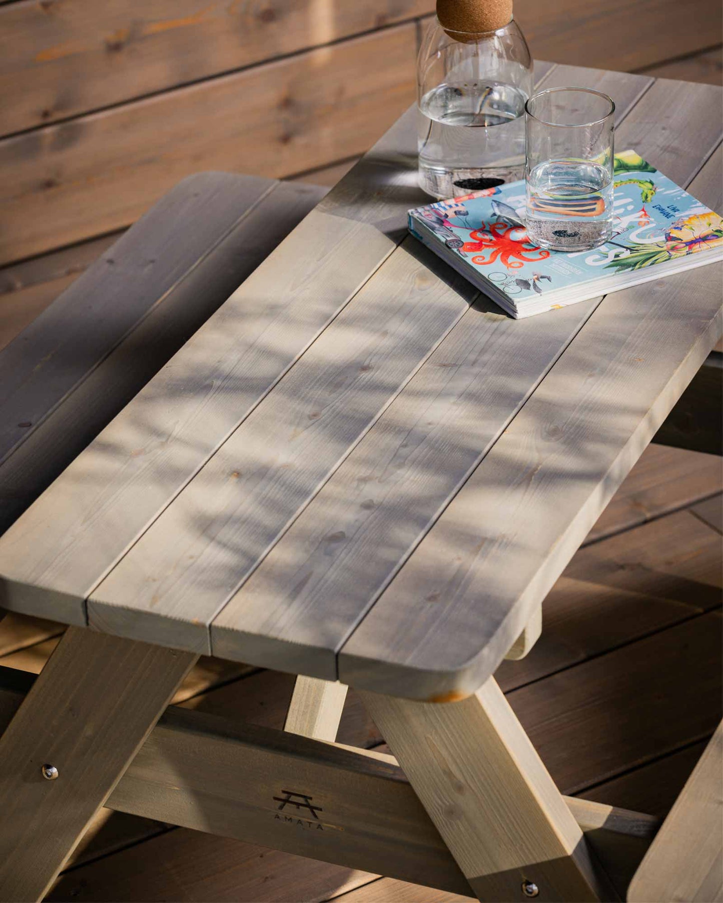 Grey garden picnic table for kids with a coloring book and glass of water on it