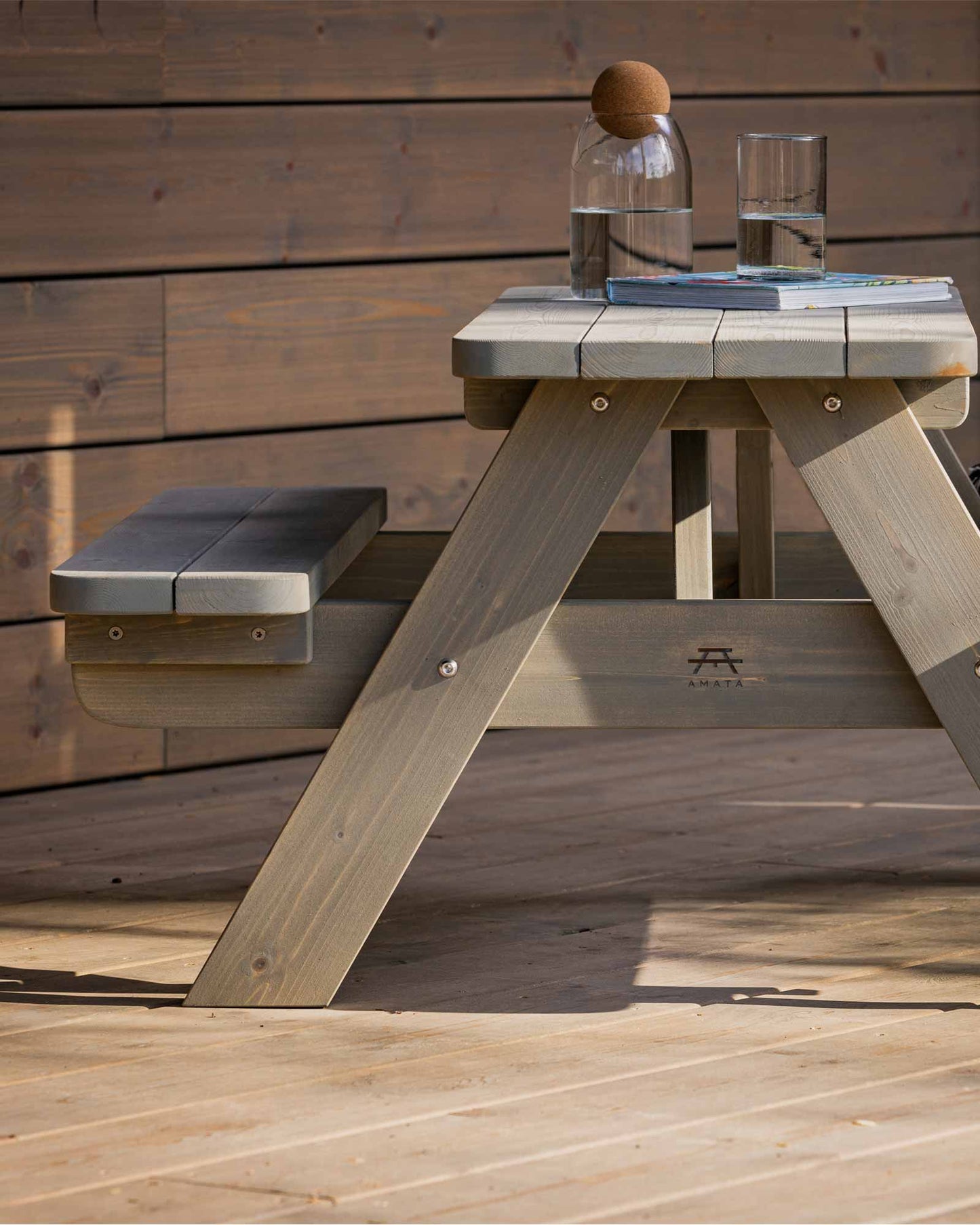 Grey children's wooden picnic table with an elegant water jug and glass on it